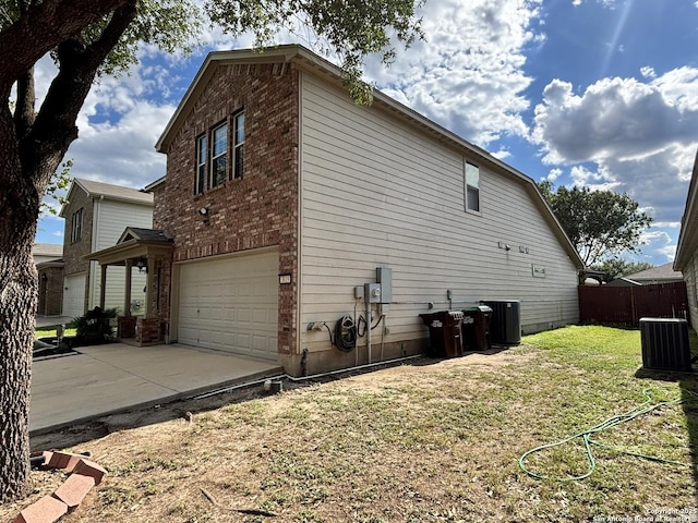 view of side of property featuring a garage, brick siding, driveway, and cooling unit