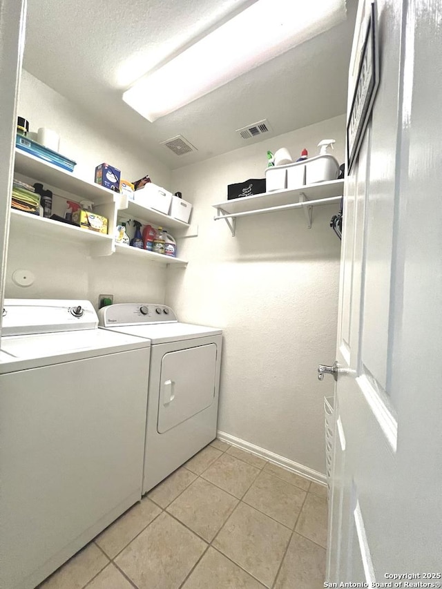 washroom with separate washer and dryer, light tile patterned flooring, and baseboards