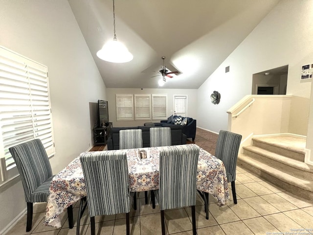 tiled dining room with high vaulted ceiling, ceiling fan, baseboards, and stairs