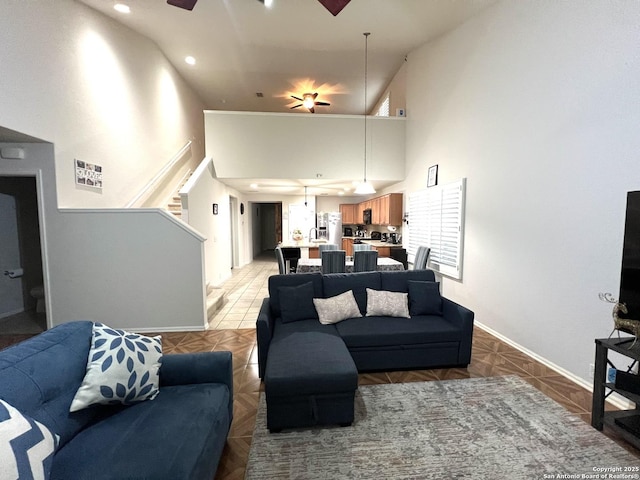 living room featuring a towering ceiling, ceiling fan, baseboards, stairs, and recessed lighting