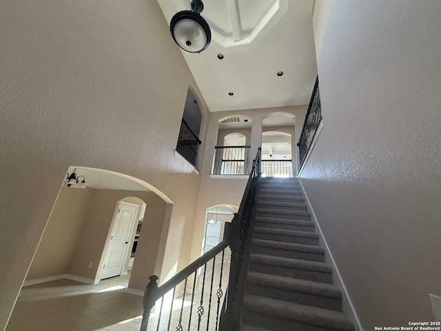 15319 Comanche, San Antonio, TX 78233 - staircase featuring arched walkways, a high ceiling, baseboards, and tile patterned floors