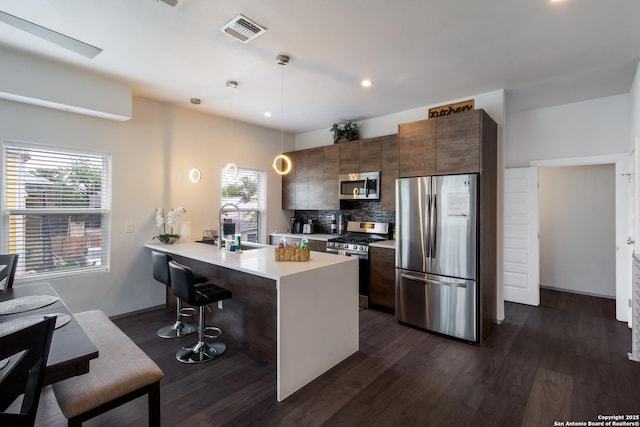 225 S Pine Unit 101, San Antonio, TX 78203 - kitchen featuring stainless steel appliances, a breakfast bar, dark wood finished floors, light countertops, and tasteful backsplash
