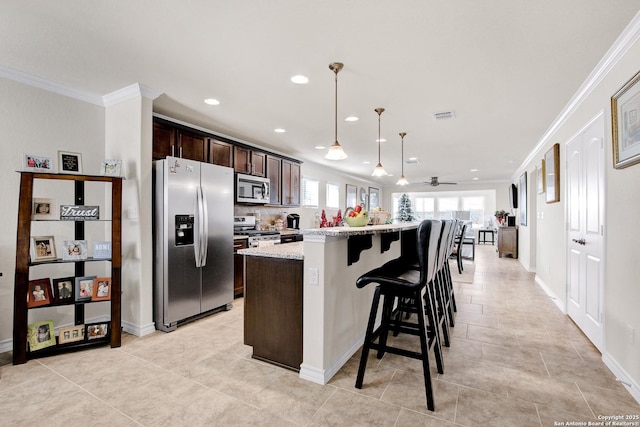 13227 Cache Crk, San Antonio, TX 78253 - kitchen featuring appliances with stainless steel finishes, ornamental molding, dark brown cabinetry, recessed lighting, and a kitchen bar