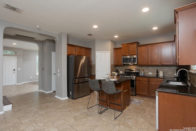 1026 Dogleg Right, San Antonio, TX 78221 - kitchen featuring appliances with stainless steel finishes, a sink, arched walkways, dark countertops, and recessed lighting