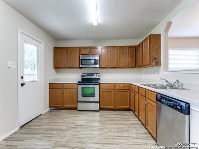 1818 Vinca Mnr, San Antonio, TX 78260 - kitchen featuring stainless steel appliances, a sink, brown cabinets, light countertops, and light wood finished floors
