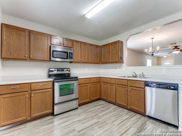 1818 Vinca Mnr, San Antonio, TX 78260 - kitchen with stainless steel appliances, a chandelier, a sink, brown cabinets, and light countertops