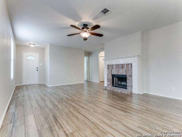 1818 Vinca Mnr, San Antonio, TX 78260 - unfurnished living room with a ceiling fan, light wood-style floors, baseboards, and a brick fireplace