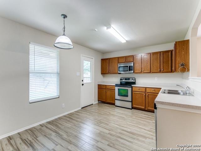 1818 Vinca Mnr, San Antonio, TX 78260 - kitchen with appliances with stainless steel finishes, a sink, brown cabinetry, light countertops, and light wood-style floors