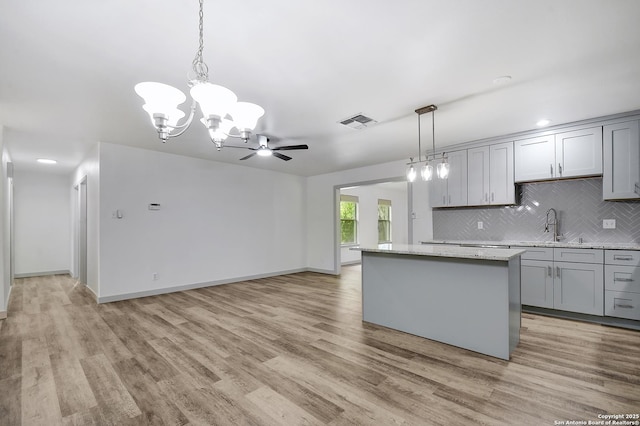 5515 Rolling Rdg, San Antonio, TX 78228 - kitchen with gray cabinetry, a center island, decorative backsplash, light wood finished floors, and recessed lighting