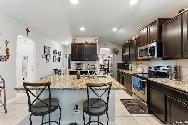 7303 Altair Loop, San Antonio, TX 78252 - kitchen with appliances with stainless steel finishes, light tile patterned flooring, a sink, a breakfast bar area, and arched walkways