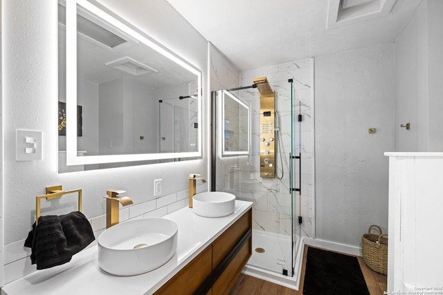 135 Fallow Dr, Kerrville, TX 78028 - bathroom featuring a marble finish shower, wood finished floors, a textured wall, double vanity, and backsplash