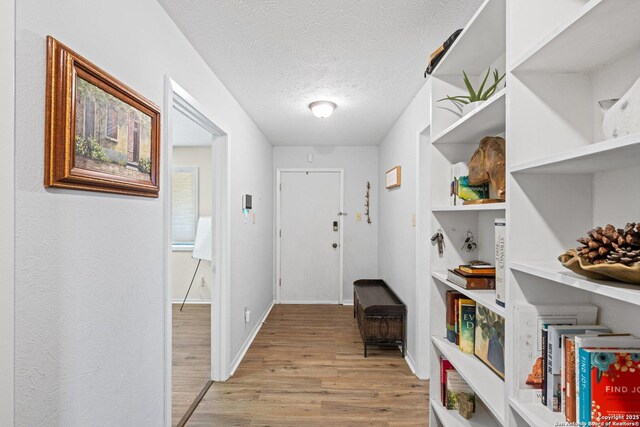 135 Fallow Dr, Kerrville, TX 78028 - hall with light wood-style flooring, a textured ceiling, and baseboards