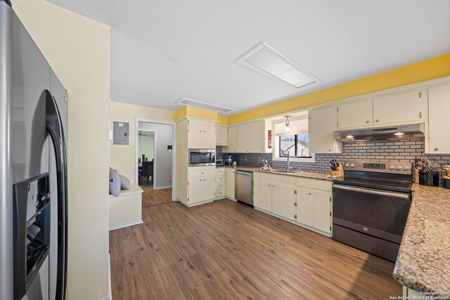 135 Fallow Dr, Kerrville, TX 78028 - kitchen featuring stainless steel appliances, under cabinet range hood, a sink, decorative backsplash, and wood finished floors