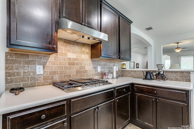 15342 Fort Marcy, San Antonio, TX 78245 - kitchen with under cabinet range hood, stainless steel gas cooktop, dark brown cabinetry, ceiling fan, and light countertops