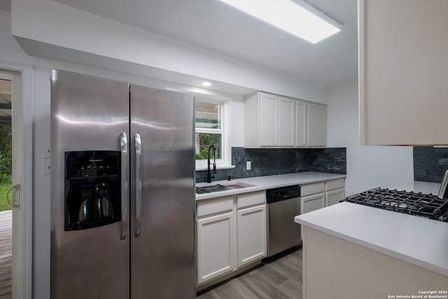 241 Weathercock Ln, Windcrest, TX 78239 - kitchen with stainless steel appliances, a sink, tasteful backsplash, light wood-style flooring, and white cabinetry