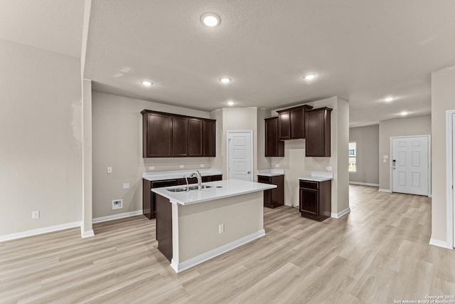 8205 Foxtail Frk, San Antonio, TX 78222 - kitchen featuring dark brown cabinets, a sink, an island with sink, light wood-type flooring, and recessed lighting