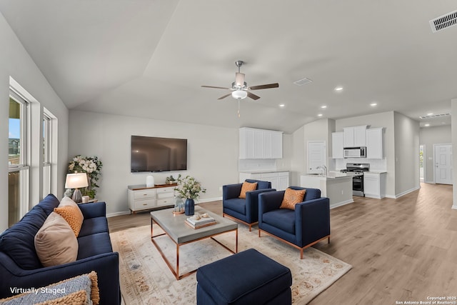 living area with ceiling fan, vaulted ceiling, light wood-style floors, baseboards, and recessed lighting