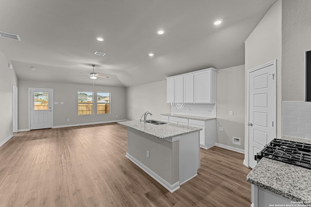 kitchen featuring a sink, backsplash, ceiling fan, wood finished floors, and baseboards
