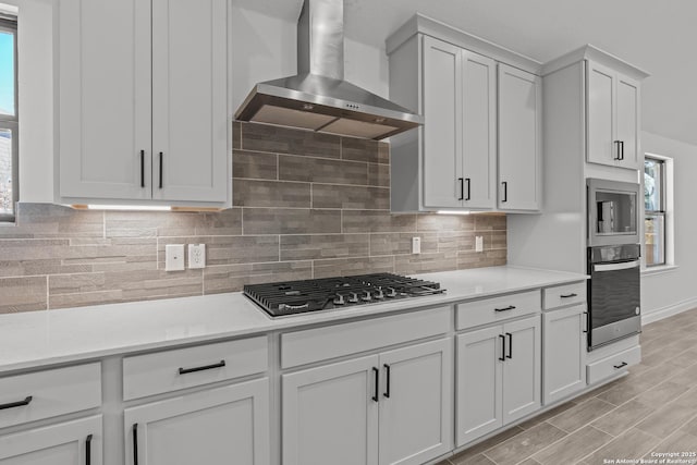 2171 Oak Run Pkwy, New Braunfels, TX 78132 - kitchen featuring stainless steel appliances, wall chimney exhaust hood, decorative backsplash, white cabinets, and baseboards
