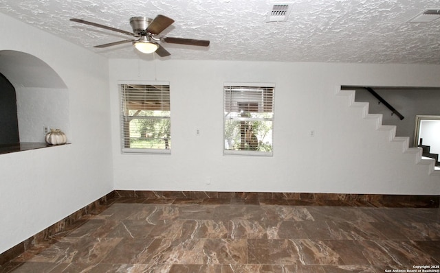 23127 Opportunity, Elmendorf, TX 78112 - unfurnished room with baseboards, arched walkways, ceiling fan, a textured ceiling, and stairs