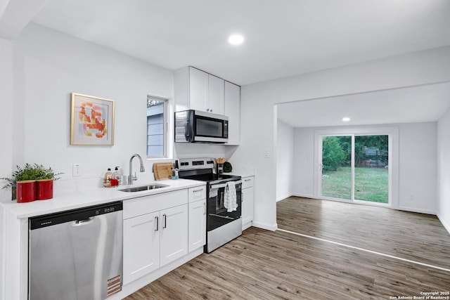 3018 Chihuahua, San Antonio, TX 78207 - kitchen featuring stainless steel appliances, light wood finished floors, a sink, white cabinetry, and light countertops