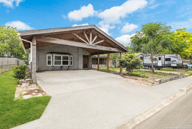 view of front of house with fence, driveway, brick siding, and a carport