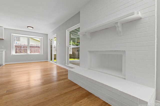 unfurnished living room with light wood finished floors, healthy amount of natural light, and baseboards