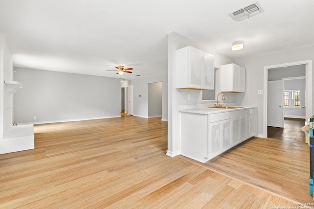 kitchen featuring a sink, light countertops, ceiling fan, white cabinets, and baseboards