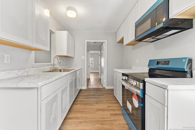 kitchen featuring stainless steel electric range, black microwave, a sink, white cabinetry, and light wood-style flooring