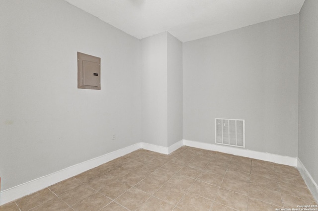 empty room with electric panel, baseboards, and light tile patterned floors