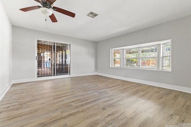 spare room with plenty of natural light, wood finished floors, a ceiling fan, and baseboards