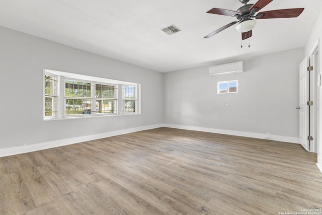 unfurnished room featuring a wall mounted air conditioner, healthy amount of natural light, and light wood finished floors