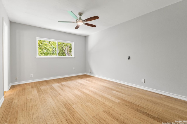 empty room with a ceiling fan, light wood-style flooring, and baseboards