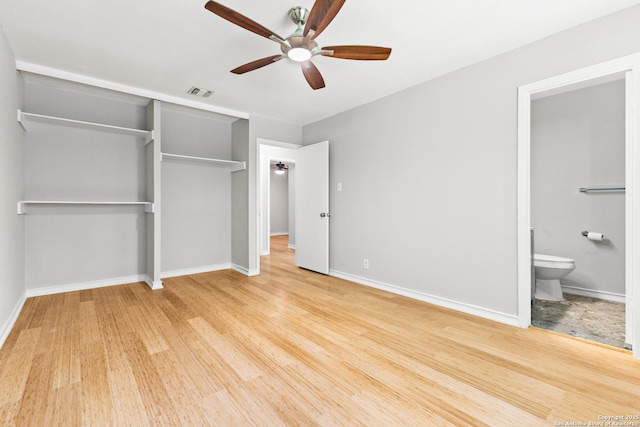 unfurnished bedroom featuring a closet, baseboards, wood finished floors, connected bathroom, and a ceiling fan