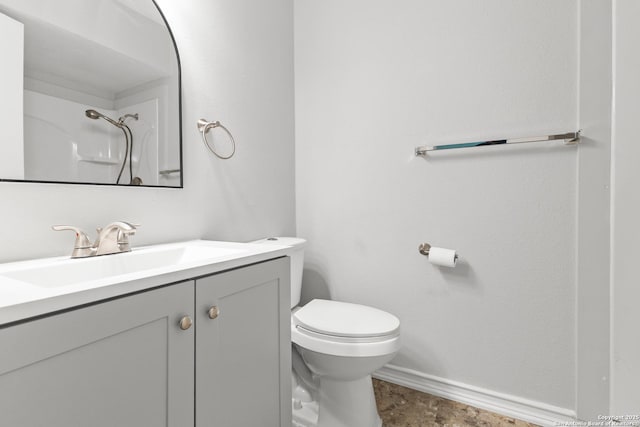 bathroom with toilet, vanity, baseboards, and a shower