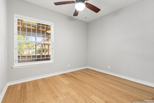 empty room with wood finished floors, a ceiling fan, and baseboards