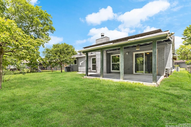 back of property featuring a chimney, a patio, brick siding, and a ceiling fan