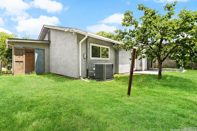 rear view of house with central AC, brick siding, and a patio area