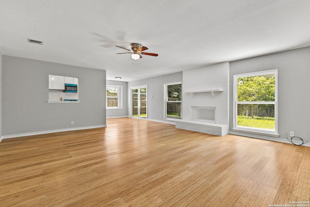 unfurnished living room featuring a ceiling fan, light wood-style floors, and plenty of natural light