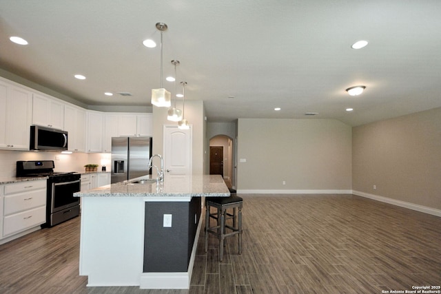565 Rosemellow, New Braunfels, TX 78132 - kitchen featuring appliances with stainless steel finishes, arched walkways, dark wood-type flooring, a kitchen island with sink, and baseboards