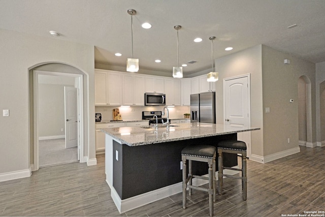 565 Rosemellow, New Braunfels, TX 78132 - kitchen featuring stainless steel appliances, a sink, arched walkways, wood finished floors, and white cabinetry