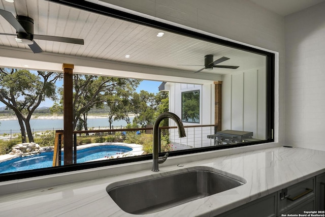772 Lakebreeze, Canyon Lake, TX 78133 - kitchen view of a ceiling fan, a sink, a water view, and light stone counters