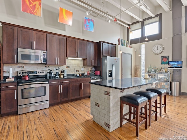 1339 S Flores St Unit 103, San Antonio, TX 78204 - kitchen featuring stainless steel appliances, a high ceiling, dark countertops, a sink, and a breakfast bar