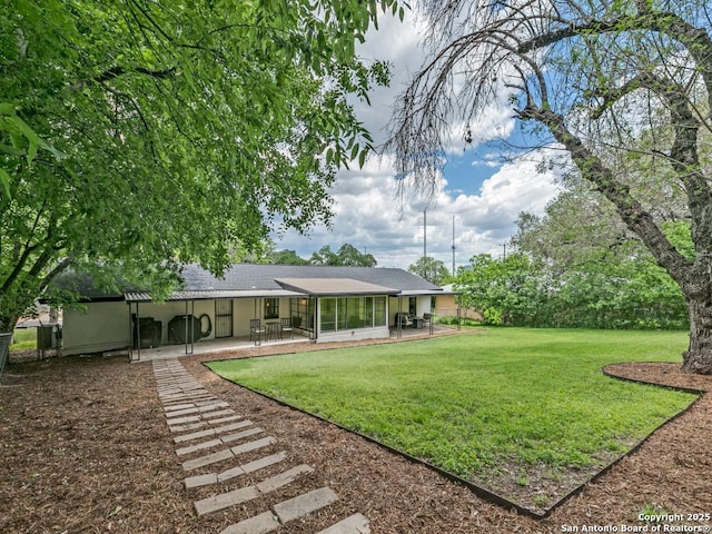 view of grassy yard featuring a patio and a sunroom