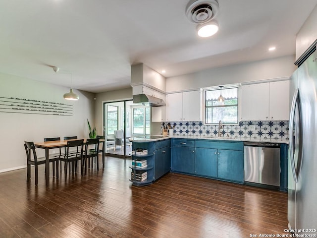 kitchen featuring stainless steel appliances, a sink, blue cabinetry, white cabinets, and healthy amount of natural light