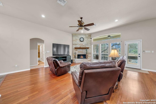 108 Medora Br, Floresville, TX 78114 - living room with light wood-style floors, a ceiling fan, a stone fireplace, arched walkways, and baseboards