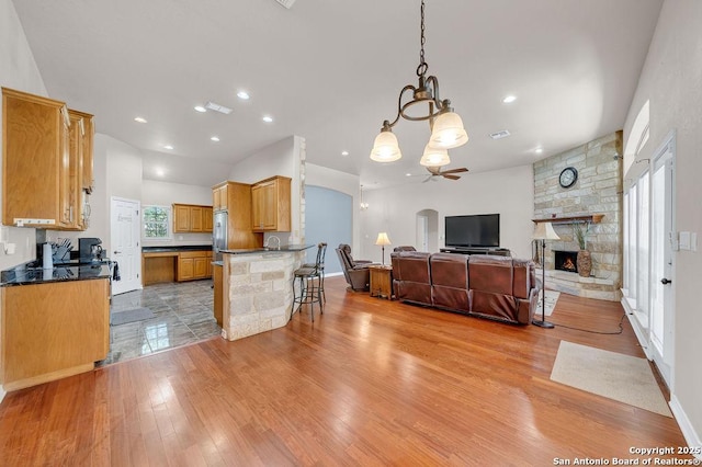 108 Medora Br, Floresville, TX 78114 - kitchen with ceiling fan, open floor plan, light wood-style flooring, a chandelier, and a fireplace