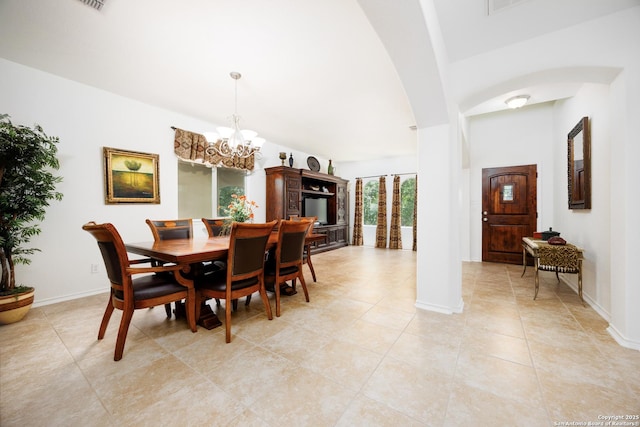 dining space with arched walkways, a chandelier, light tile patterned floors, and baseboards