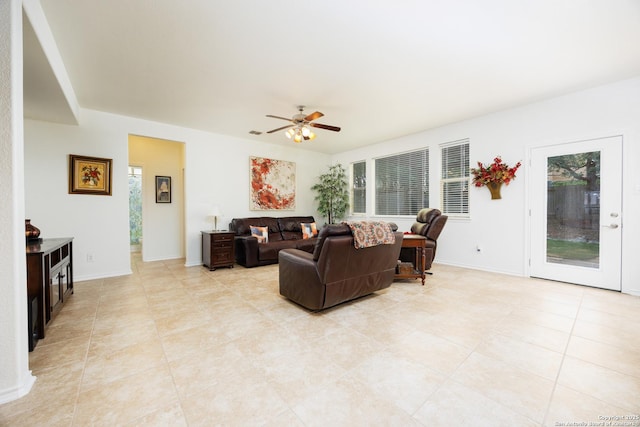 living area with a ceiling fan, light tile patterned flooring, and baseboards