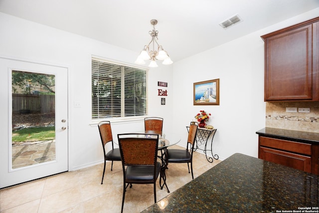 dining area with a chandelier, light tile patterned floors, and baseboards